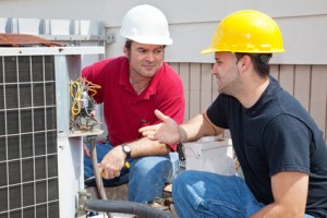 Air conditioning repairmen discussing the problem with a compressor unit.